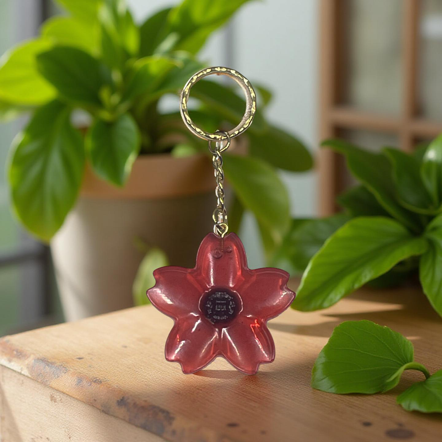 Flower-shaped keychain on a wooden surface with plants in the background